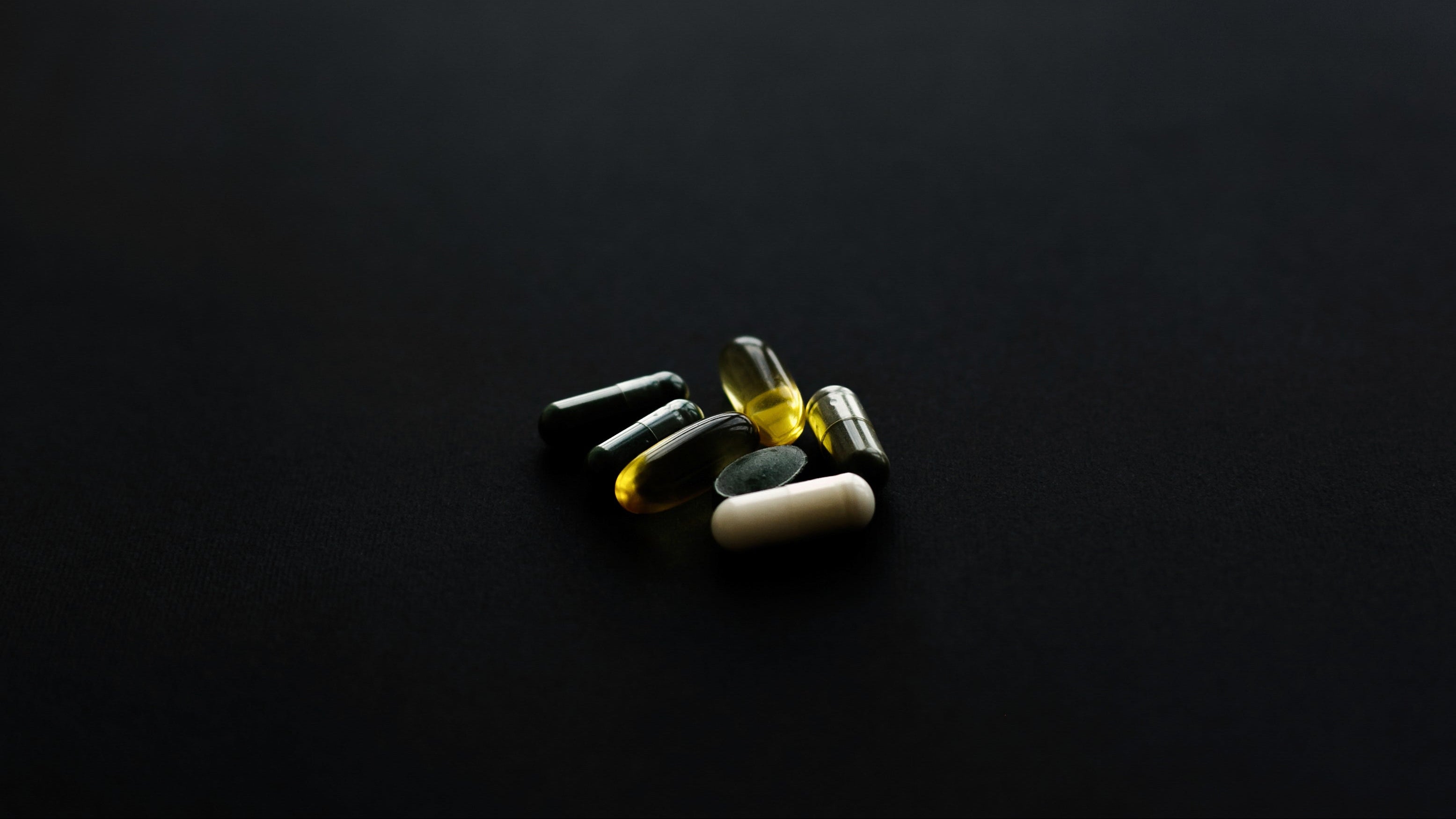 Assorted pills and vitamins on a black background